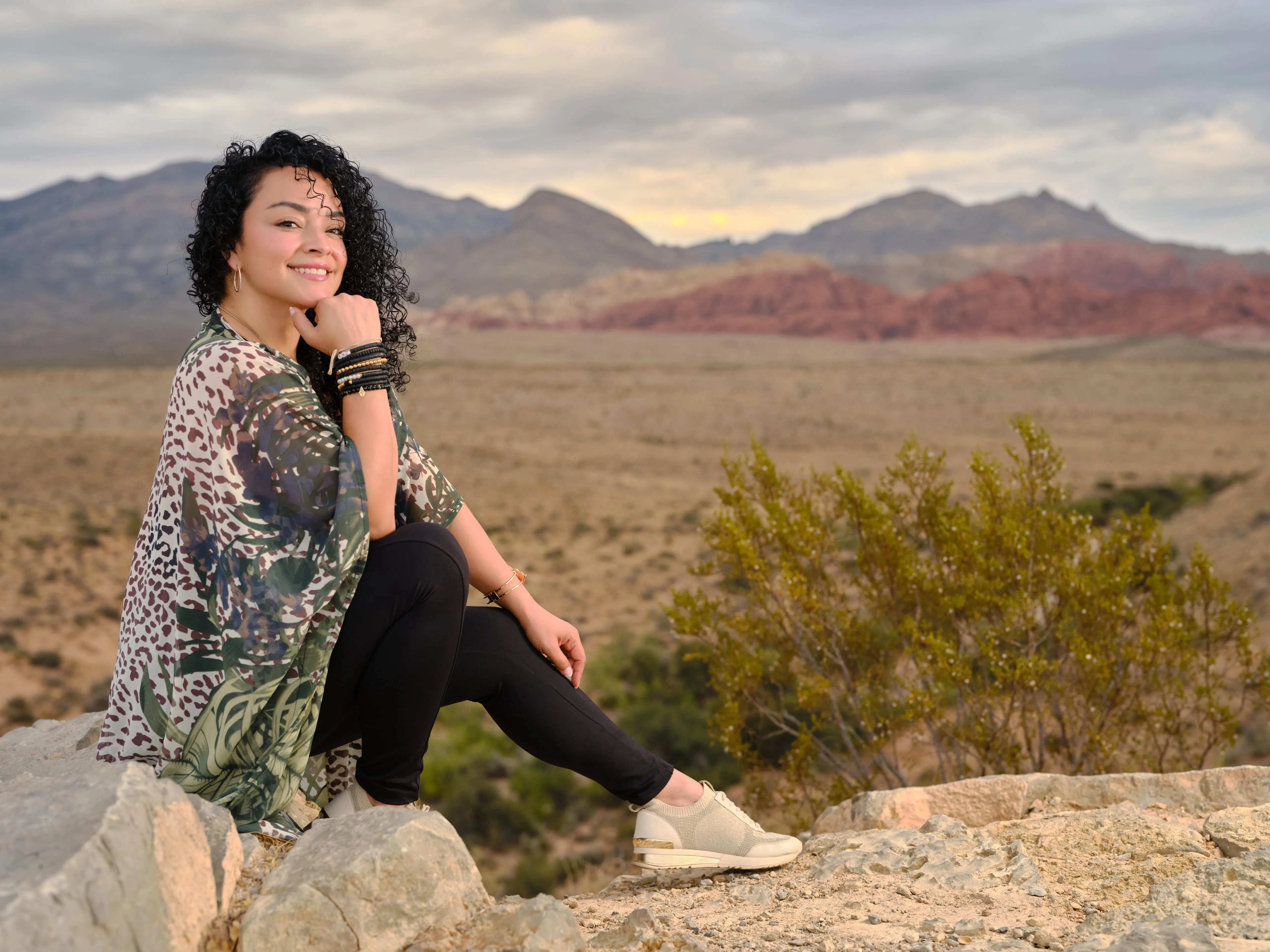 Woman sitting on a rock, smiling at sunset, symbolizing healing and peace.