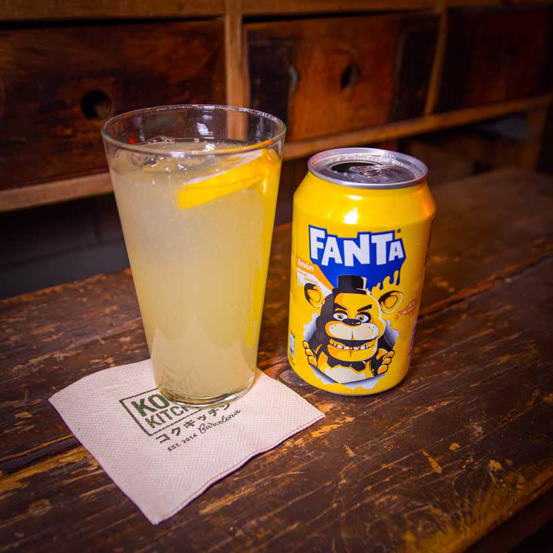 Glass of cold Fanta Lemon soda with ice, a bright and refreshing citrus beverage