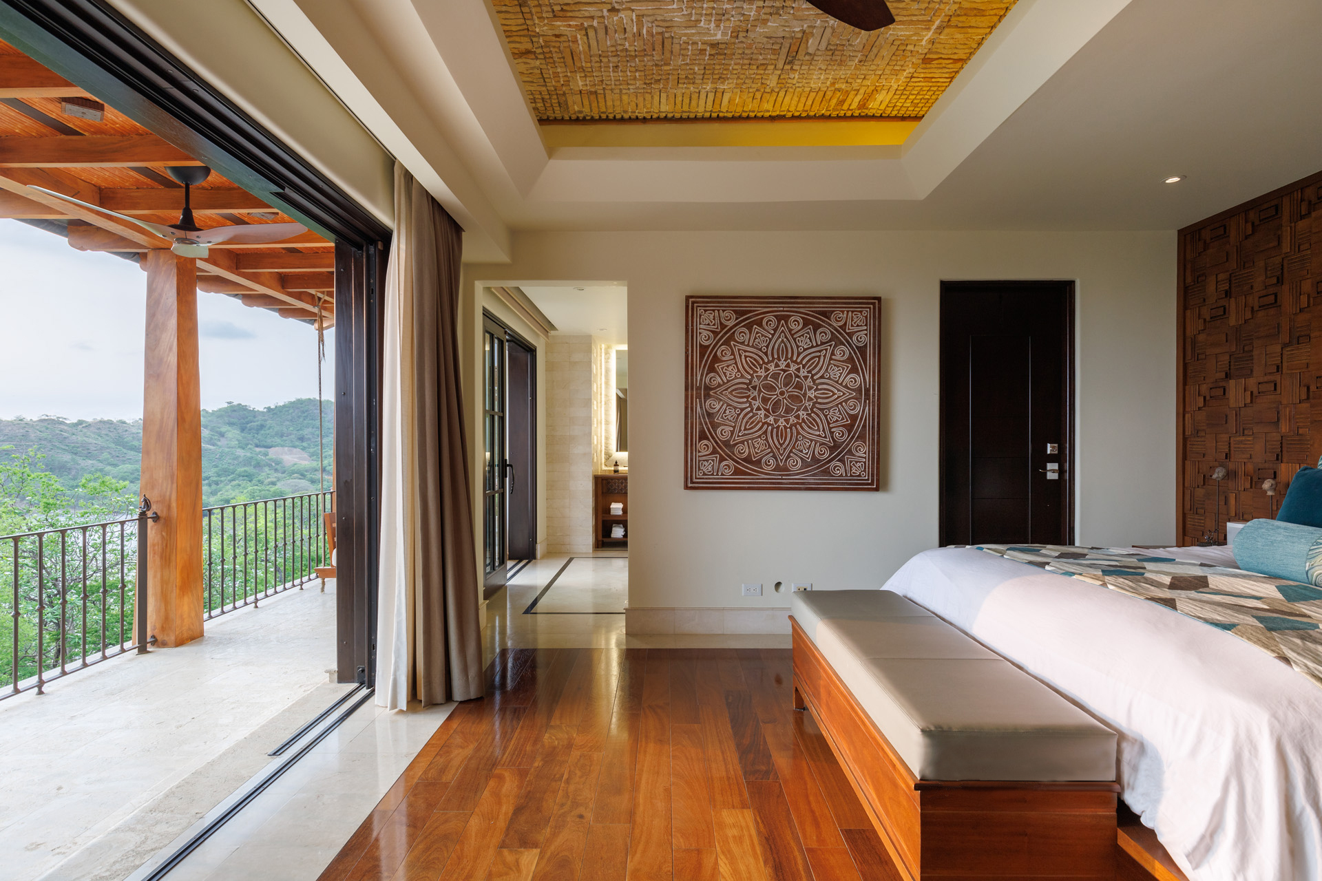 Luxury villa primary suite opening onto a terrace with jungle and hillside views