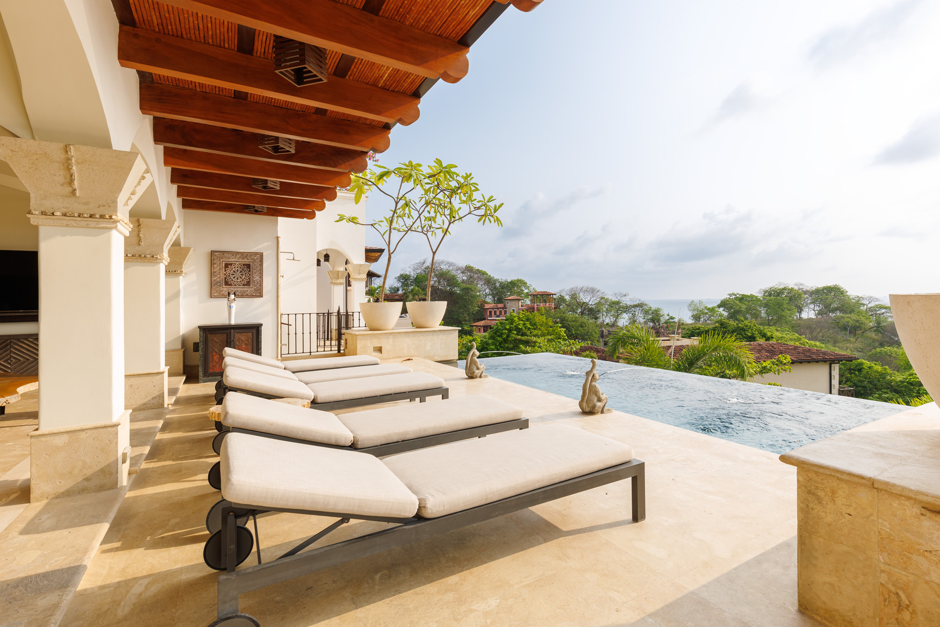 Covered terrace with loungers overlooking the infinity pool and coastline at a luxury Costa Rica villa