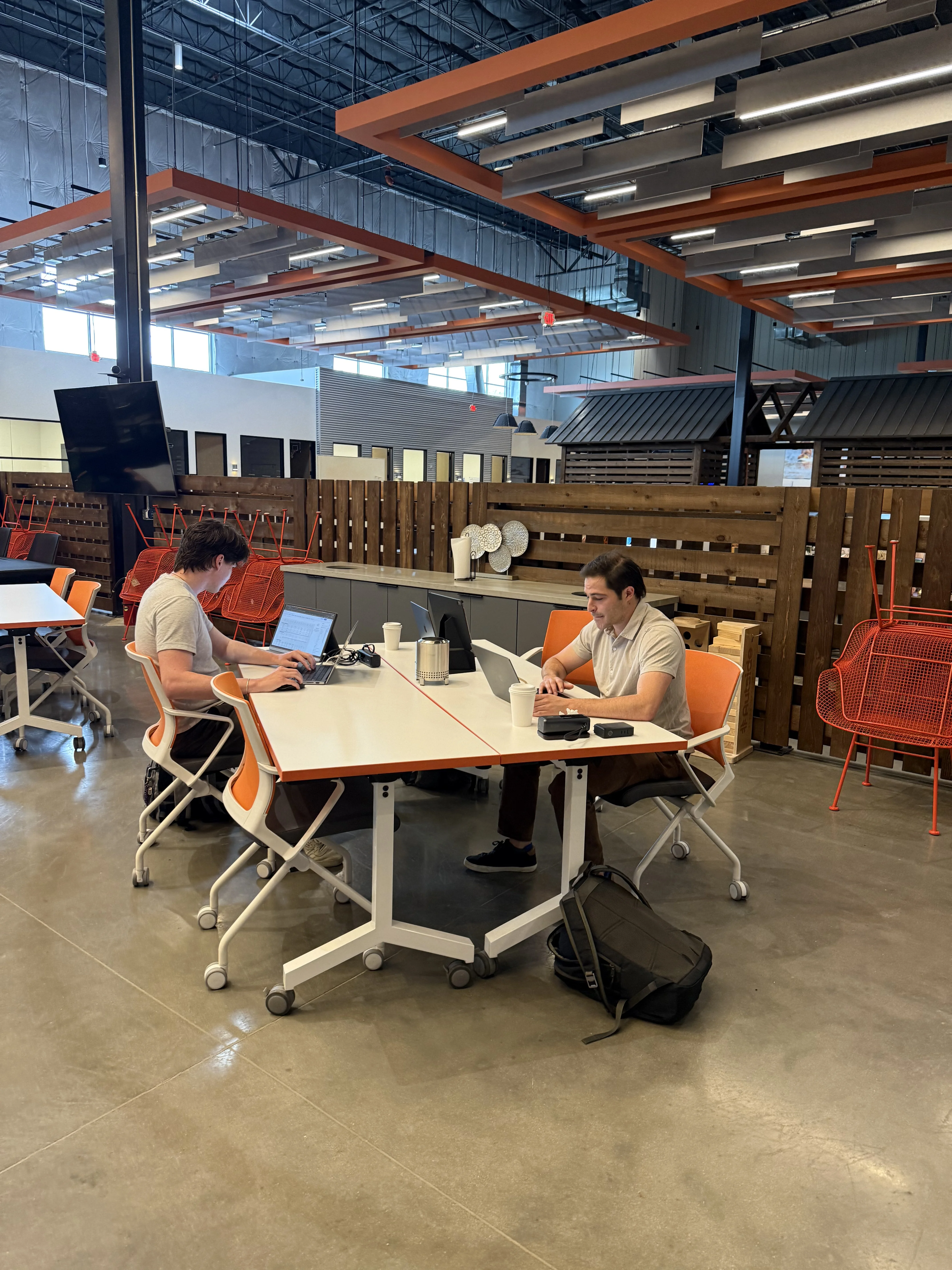 Two marketers working on laptops at a shared table in an open office