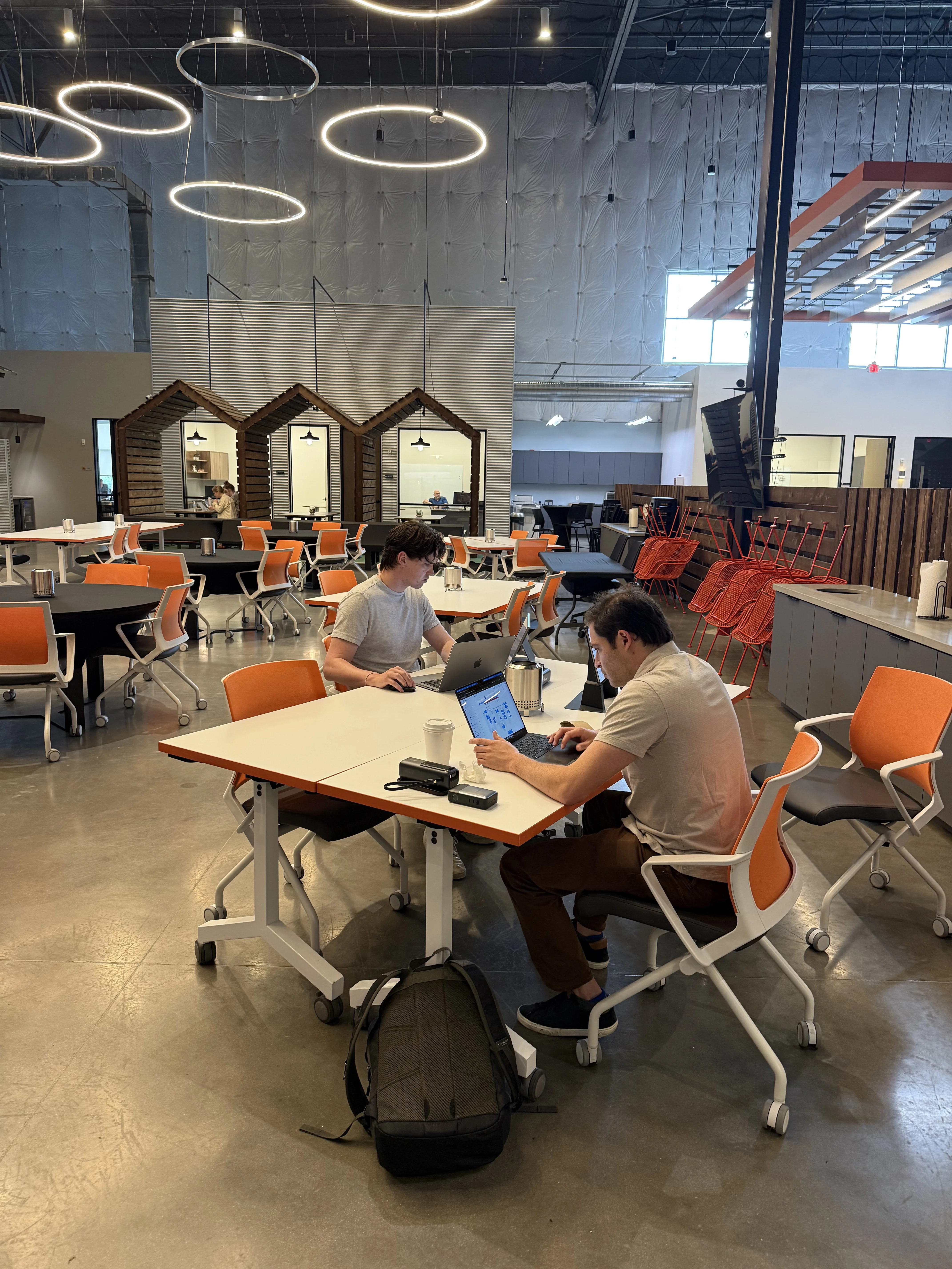 Two marketers working on laptops at a shared table in an open office