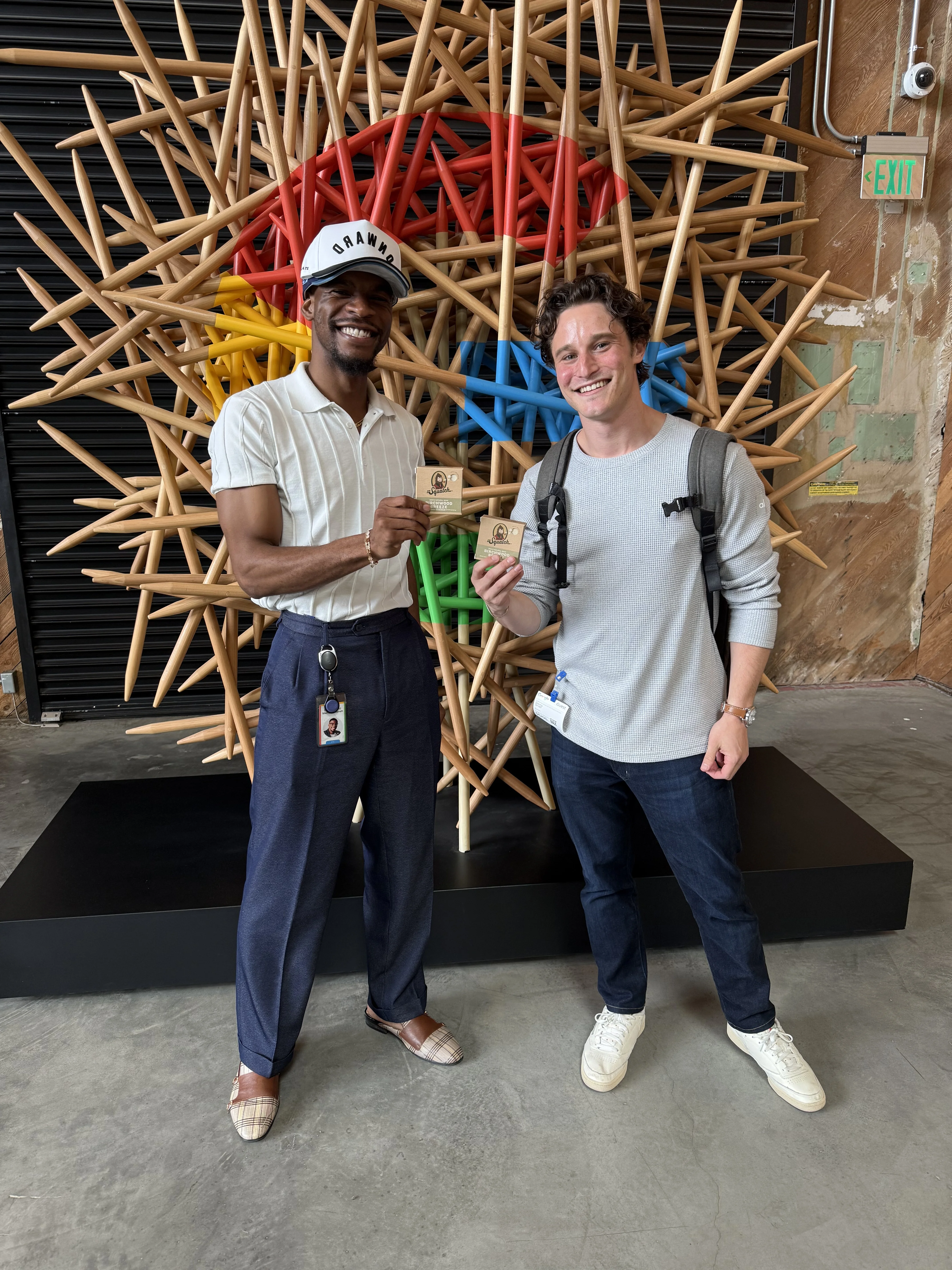 Two members of the Onward team smiling in front of a colorful art installation