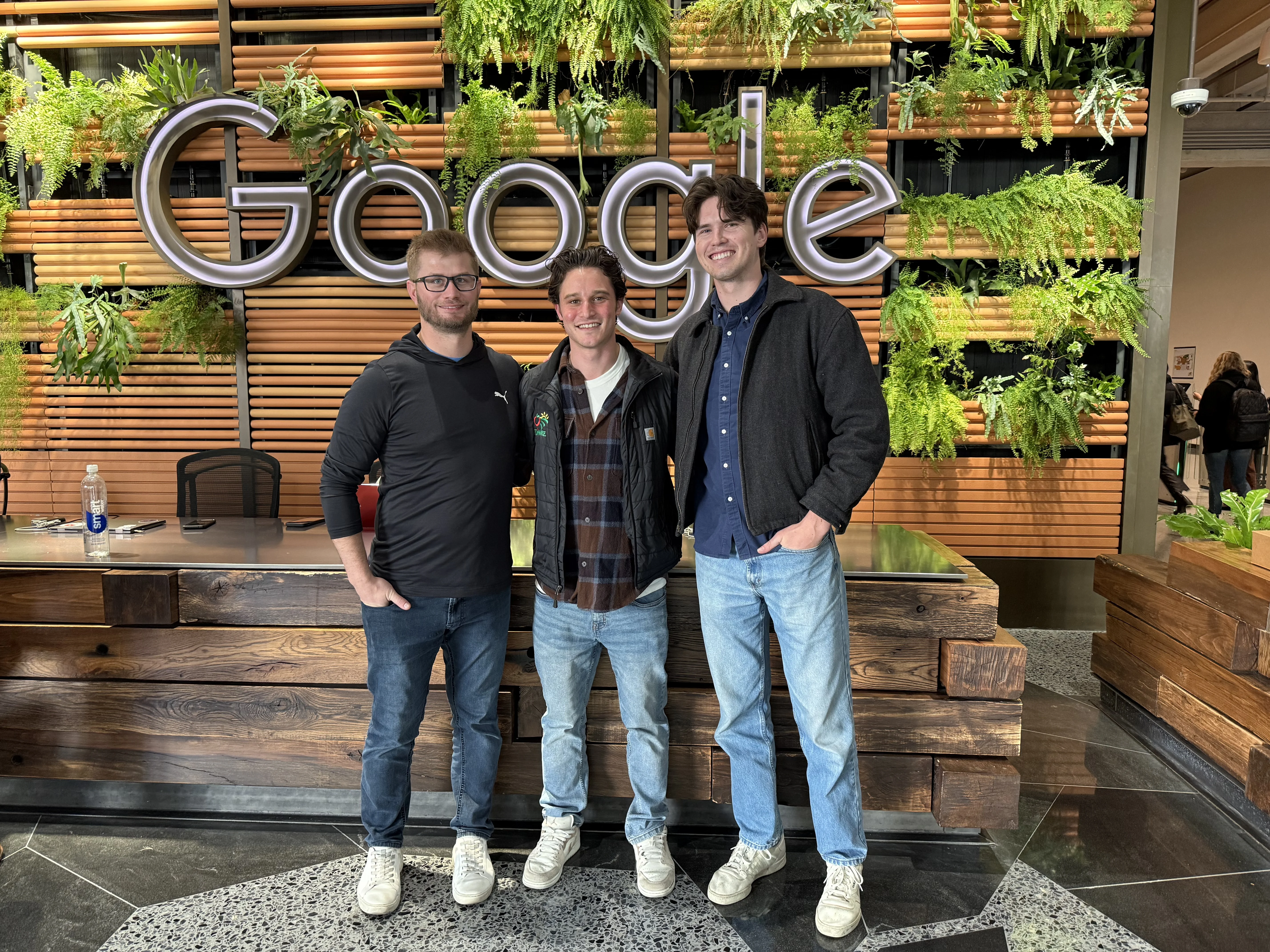 Three members of the Onward team standing in front of the Google logo plant wall