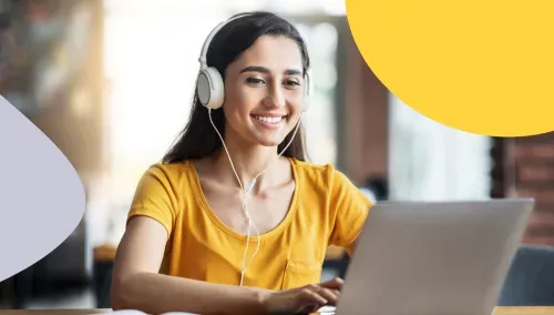 Woman wearing headphones smiling while working on a laptop
