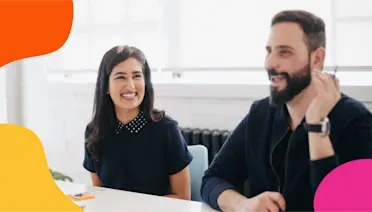 Two coworkers laughing together during a discussion at a table