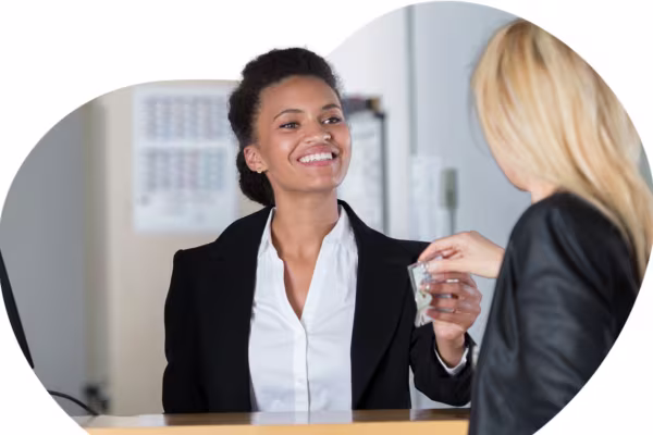 A hotel receptionist smiling and handing a room key to a guest