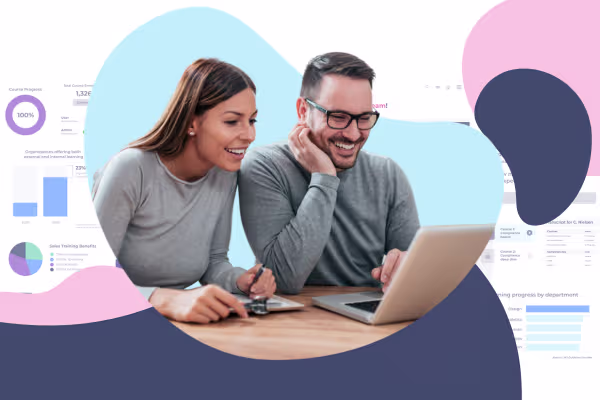 Two colleagues smiling while reviewing training data on a laptop together