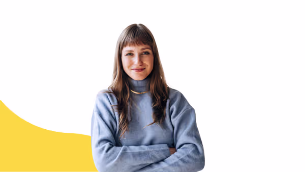 A woman in a blue sweater smiling with arms crossed
