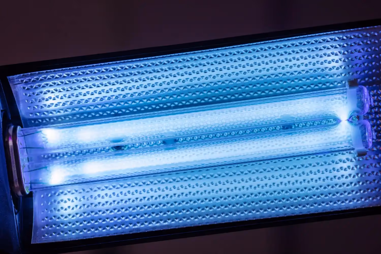 A close-up of a glowing blue UV light bulb inside an air purifier.