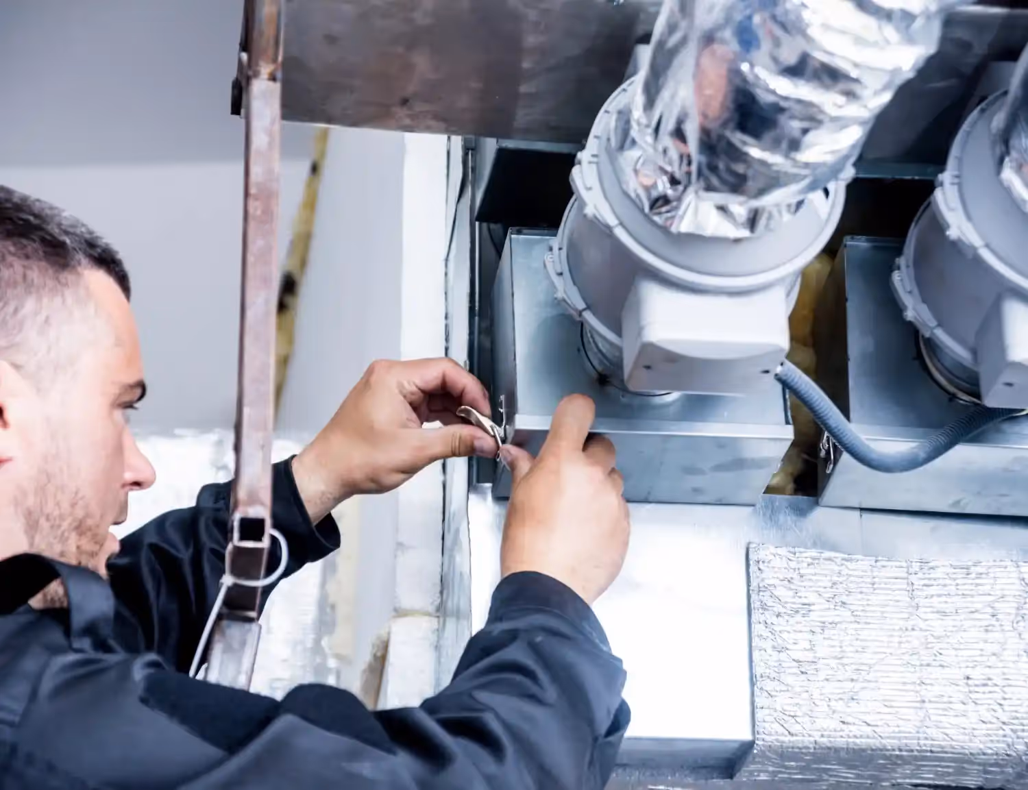 A repairman fixing a commercial air duct.