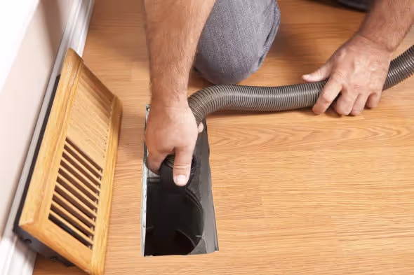 A vacuum hose in a floor vent.