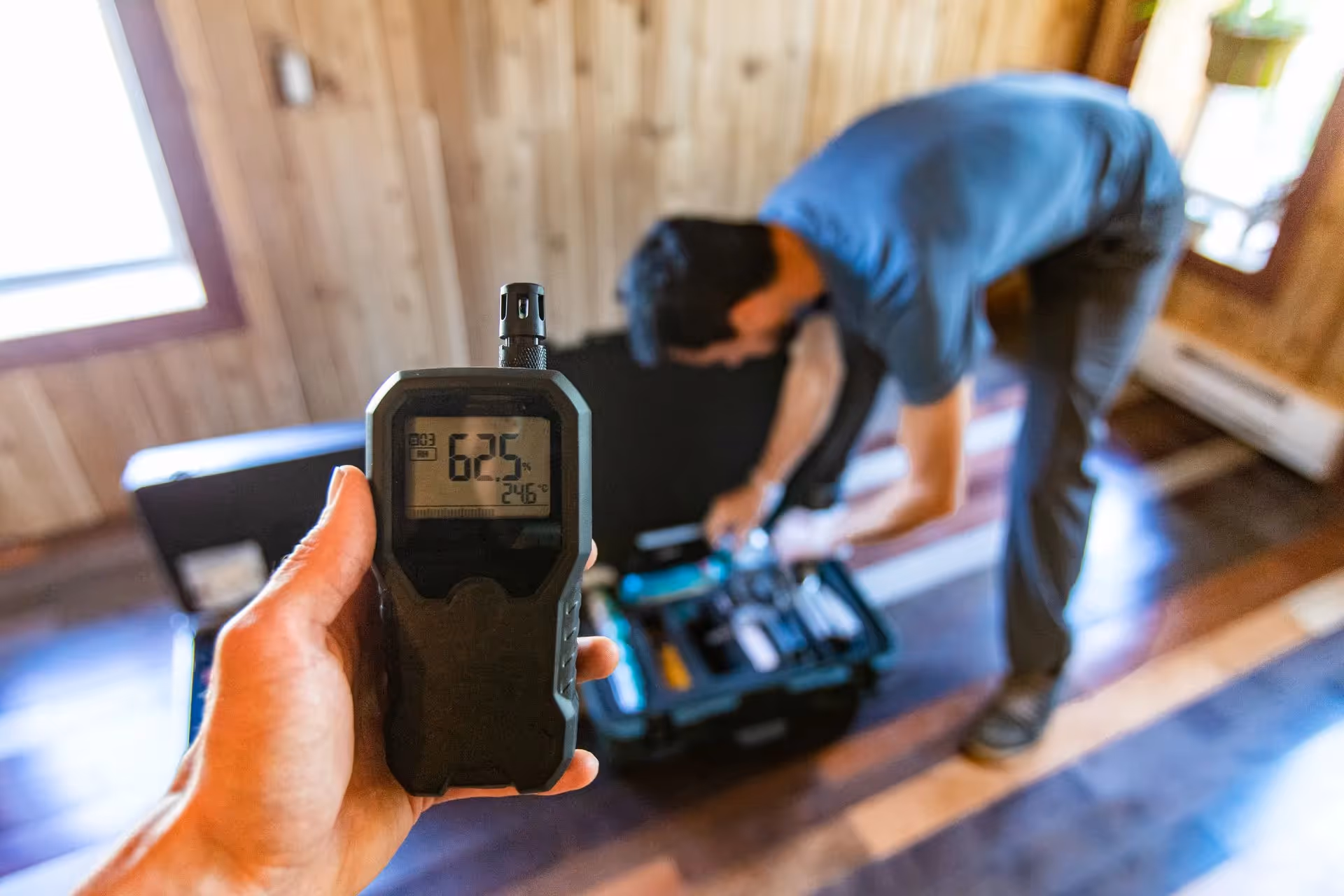 A technician holding a meter to check air quality.