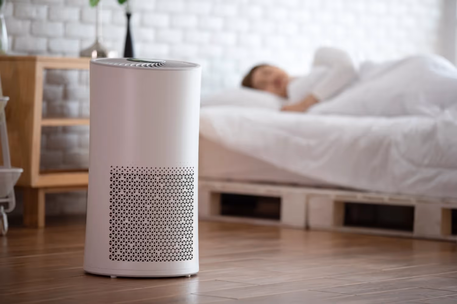 An air purifier running near a bed.