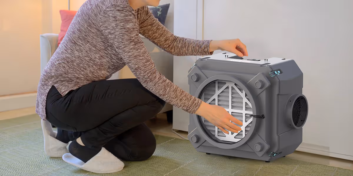 A person changing a filter in a portable air scrubber.