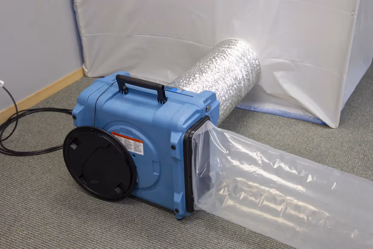 A portable air scrubber connected to ducting.