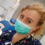 Žena v lékařském oděvu s rouškou na obličeji v nemocničním prostředí.