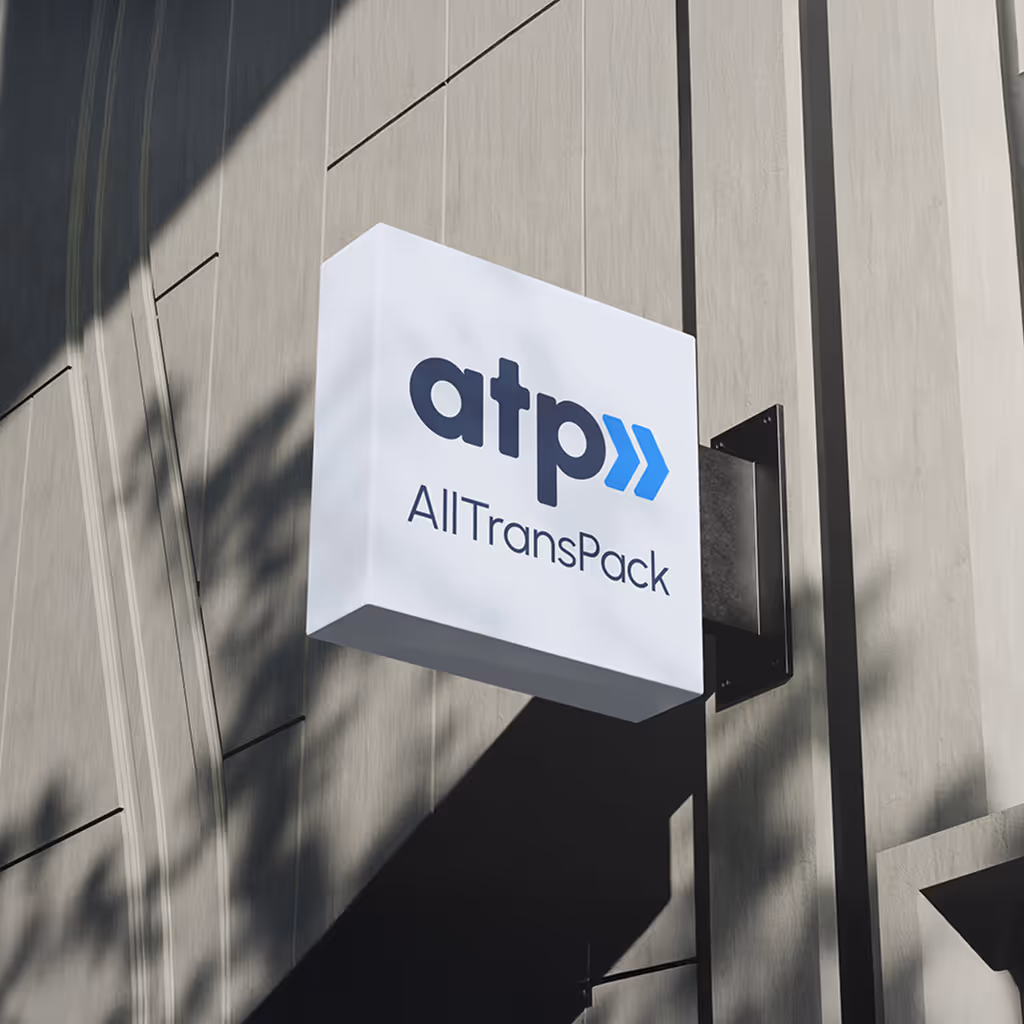 Ein weißes, außen an einer Wand montiertes Schild mit dem Logo und Text „atp AllTransPack“.