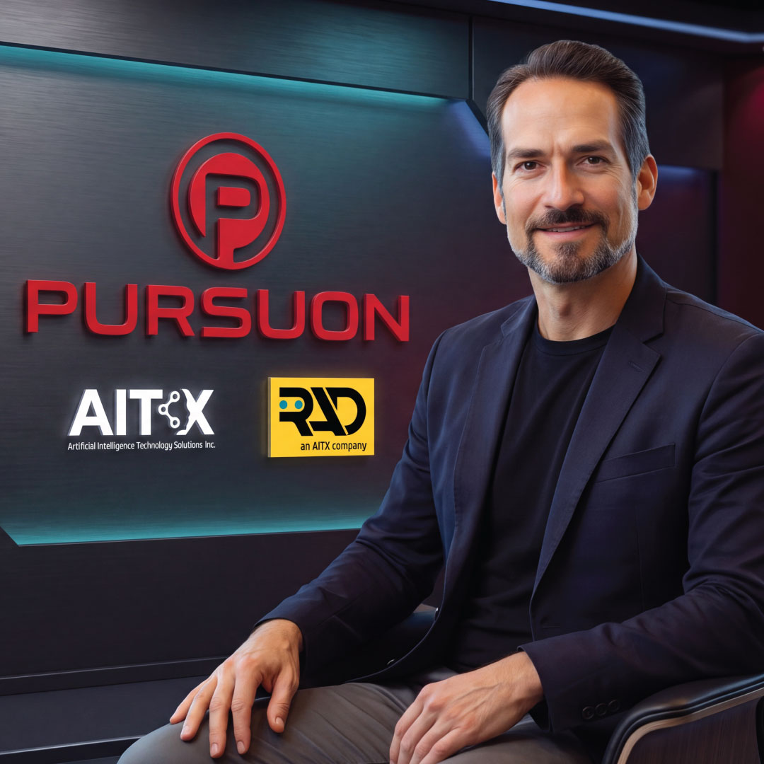 Smiling man in dark blazer seated by wall with red Pursuon and AITX logos in modern office.