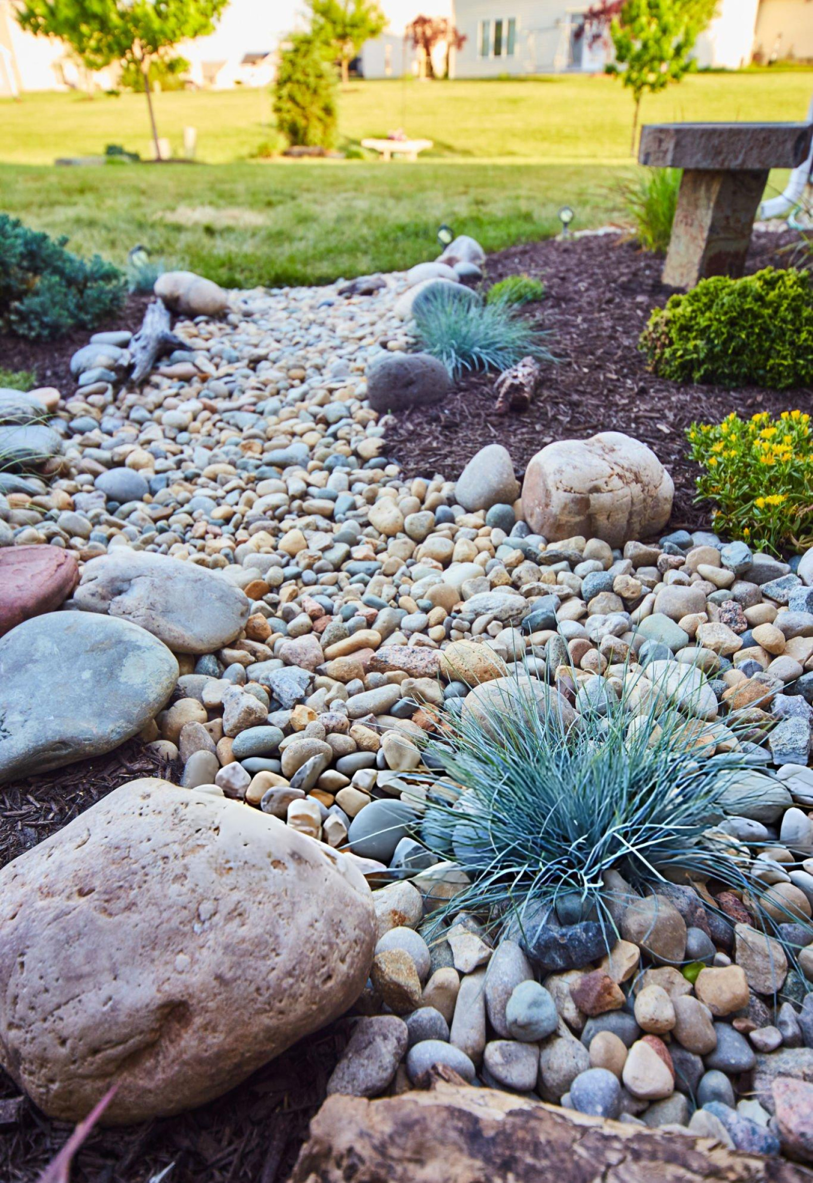 Dry creek bed landscaping with river rock, boulders and ornamental grasses for natural yard drainage