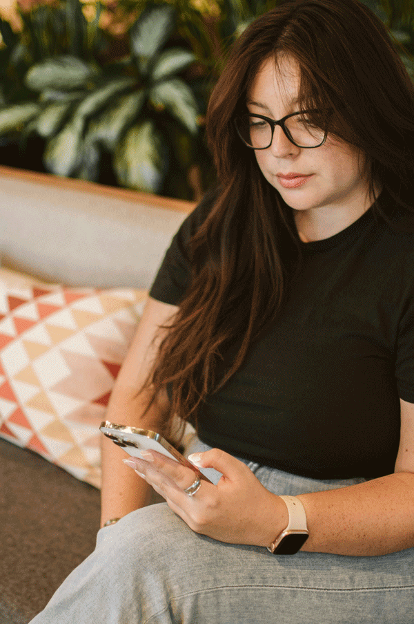 Woman in black shirt and glasses searching on phone.