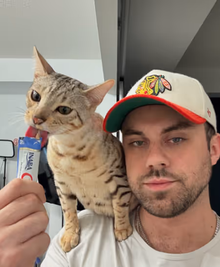Mack feeding his cat while ghost sits on his shoulder.