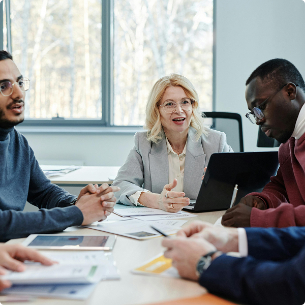 Group of diverse business professionals in a meeting discussing documents around a table in a bright office.