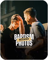 Young man being baptized in water by another man inside a dimly lit room.