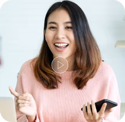Smiling young woman with shoulder-length hair holding a smartphone and gesturing with her hand.