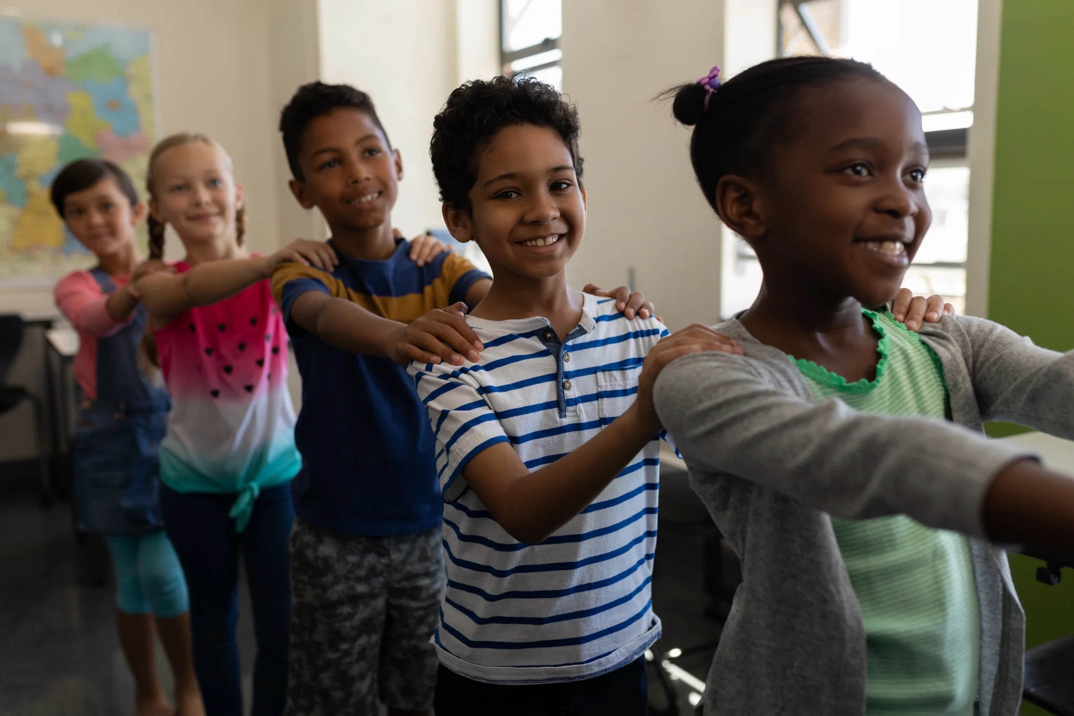 school kids in a line smiling with hands on each others shoulders
