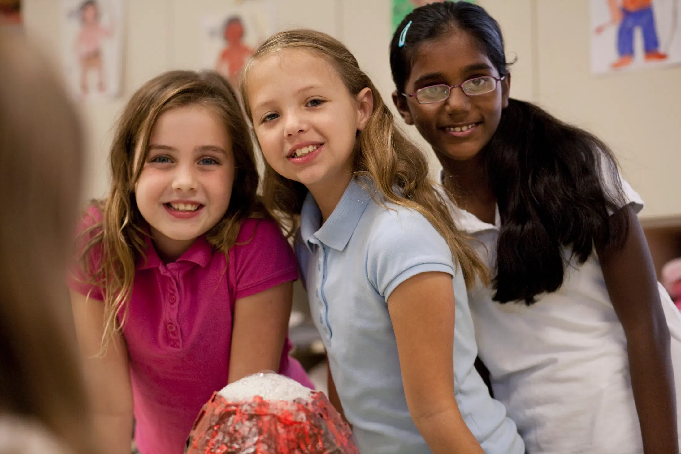 girls smiling in front of volcano model