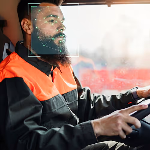Homem dirigindo veículo vestindo roupa de trabalho preta e laranja com reconhecimento facial digital sobre o rosto.
