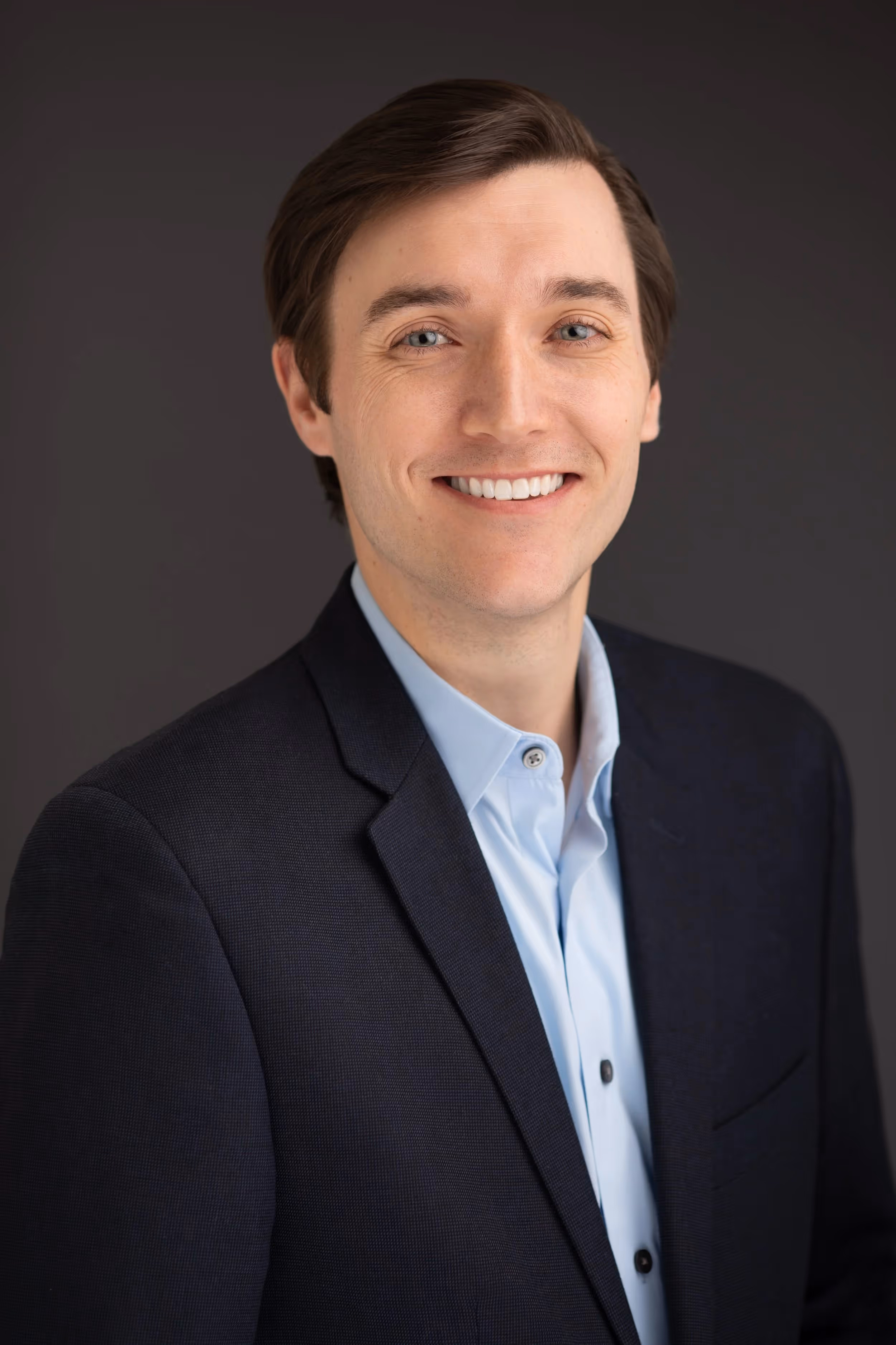 Smiling professional in navy suit and light blue shirt headshot