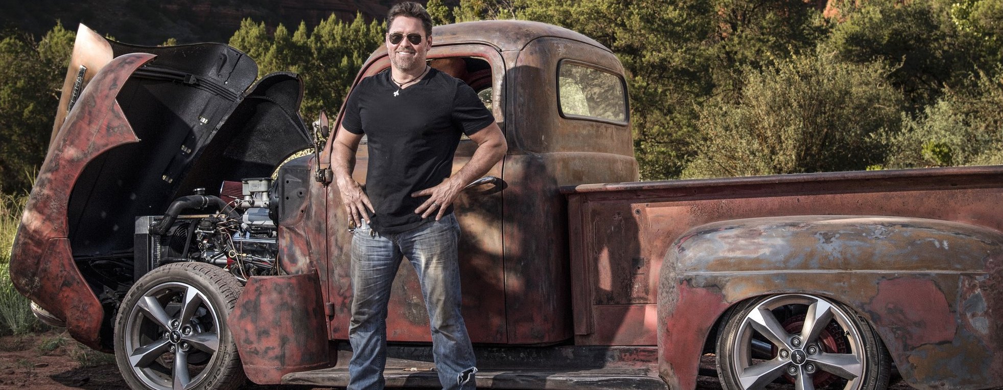 Tim McClellan standing in front of a rusted classic pickup truck