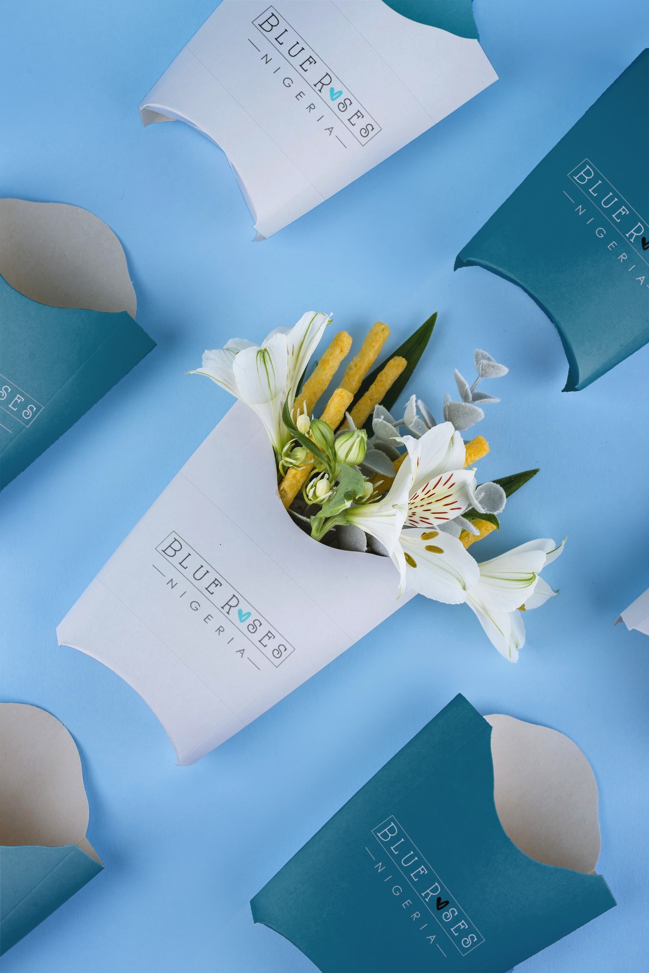 White Blue Roses Nigeria packaging with white flowers and yellow snack sticks inside against a blue background.
