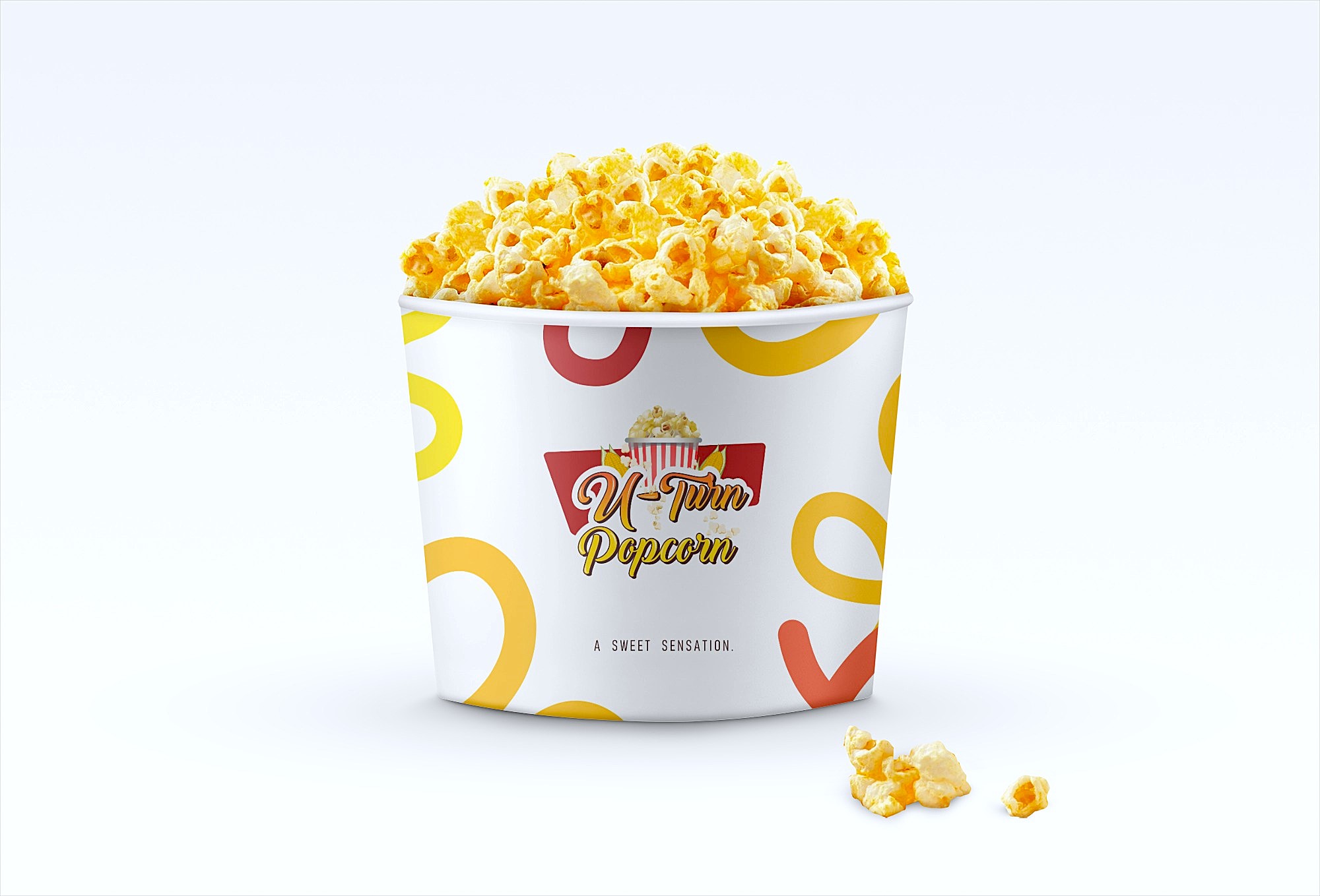 A container filled with yellow buttered popcorn labeled 'U-Turn Popcorn' with a few popcorn pieces on the white surface nearby.