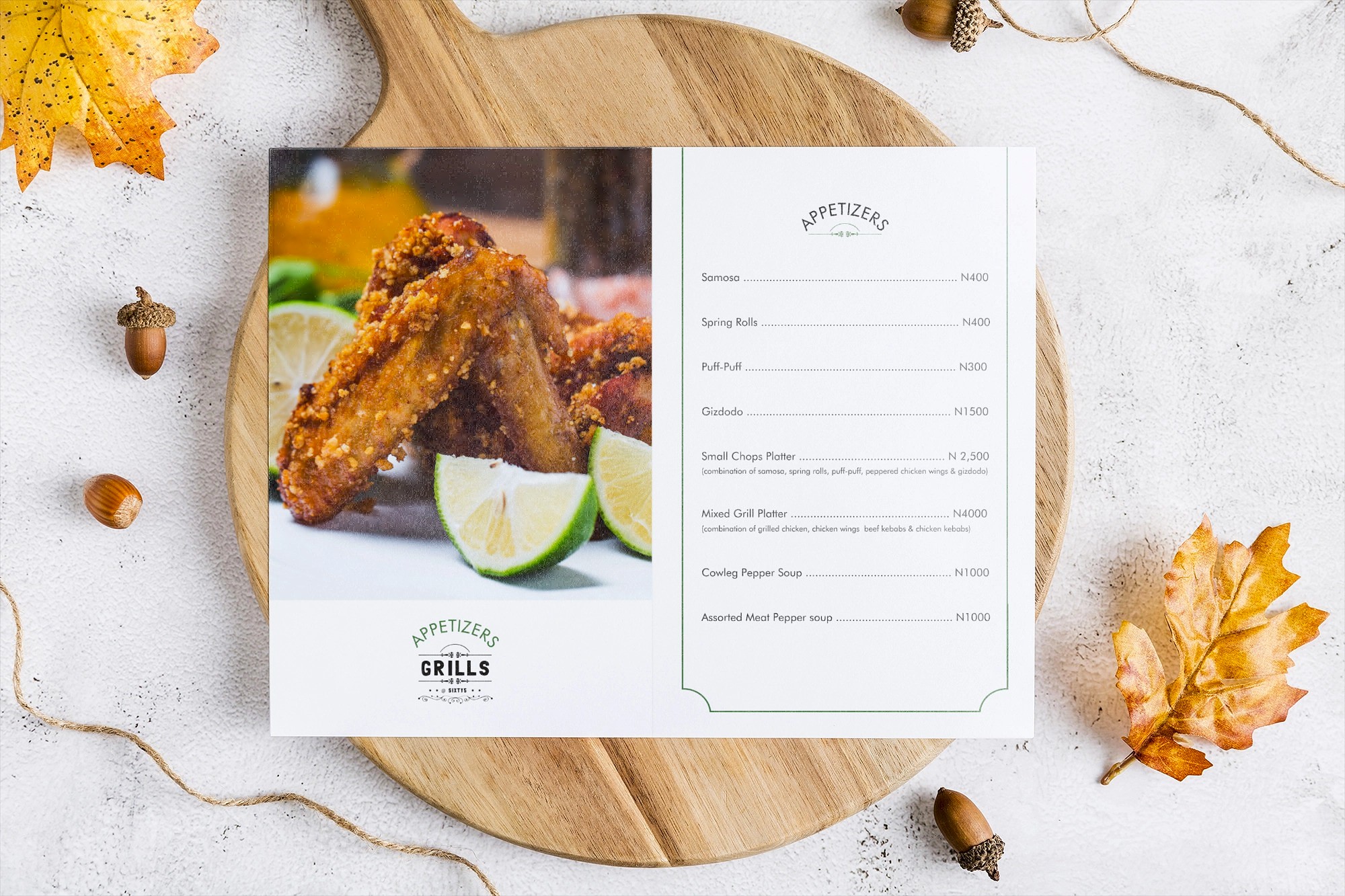 Restaurant appetizer menu featuring crispy chicken wings with lime wedges on a wooden board, surrounded by autumn leaves and acorns.