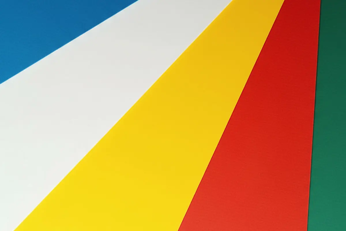 Fächerförmig angeordnete, farbige Papierbögen in Blau, Weiß, Gelb, Rot und Grün.