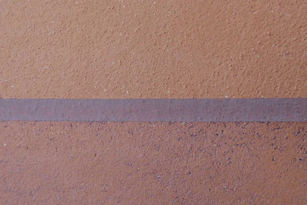 Nahaufnahme einer braunen Mauer mit horizontal verlaufendem dunklem Streifen.