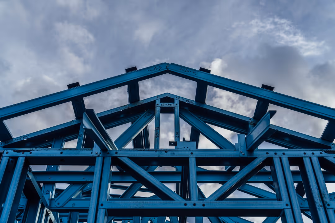 Close-up of blue steel frame structure for a building under a cloudy sky.