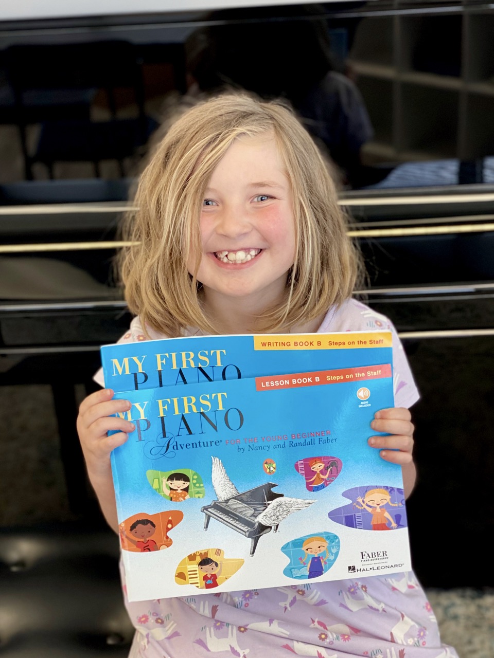 A kid playing piano while other kids on the background are watching him at a group piano lesson