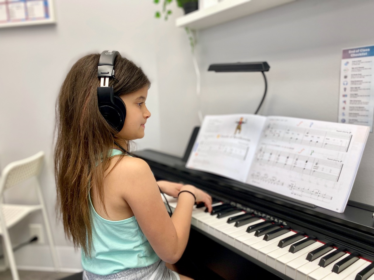 A kid with headphones sitting at a piano