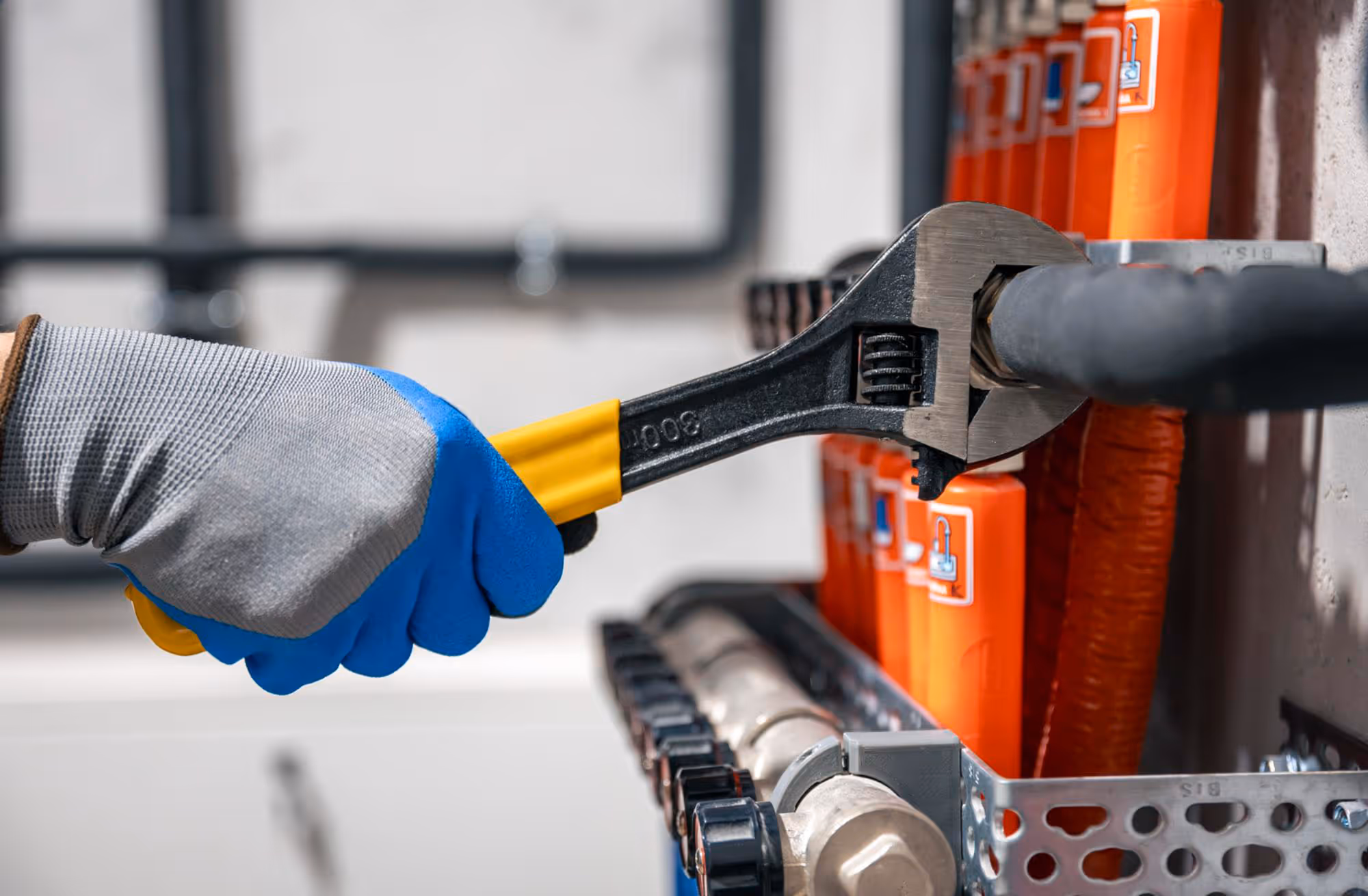 A person uses a wrench to tighten a pipe fitting on a water system.