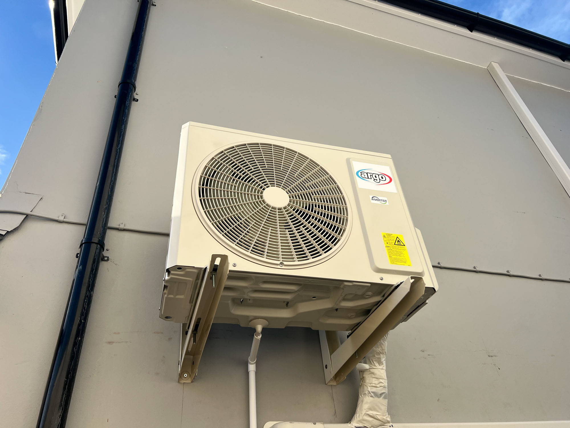A beige air conditioning unit is mounted on the exterior wall of a building.