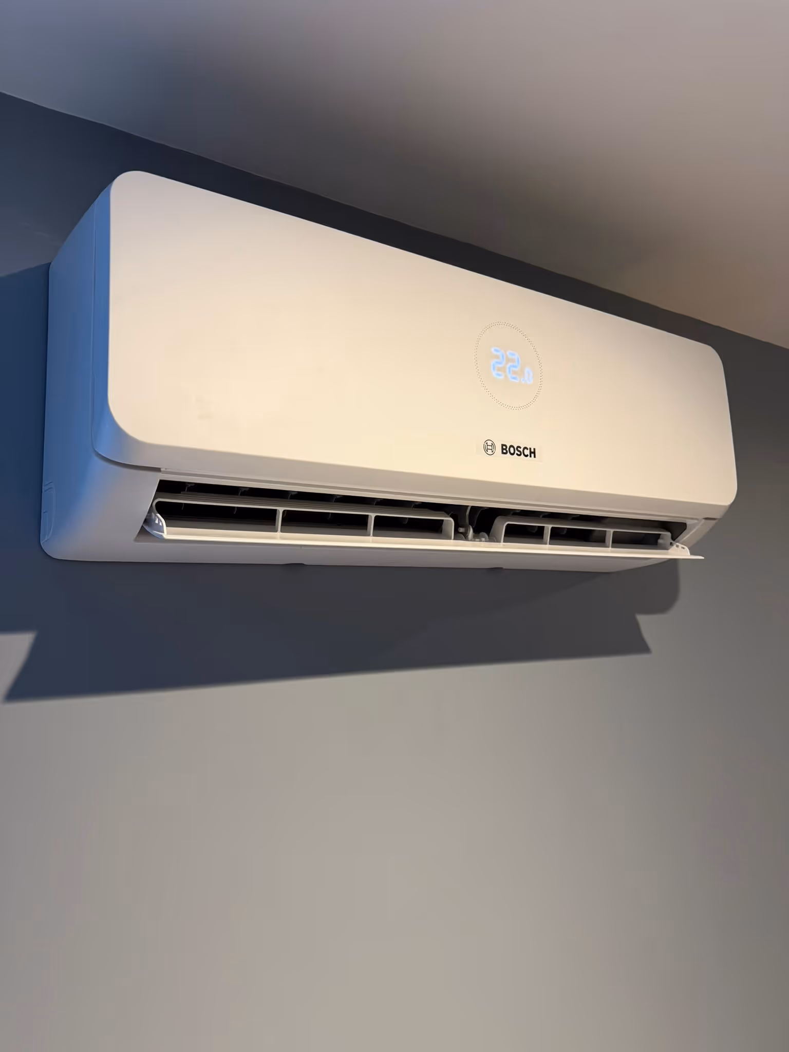 Wall-mounted air conditioner set to 22 degrees Celsius, with vents open and running.