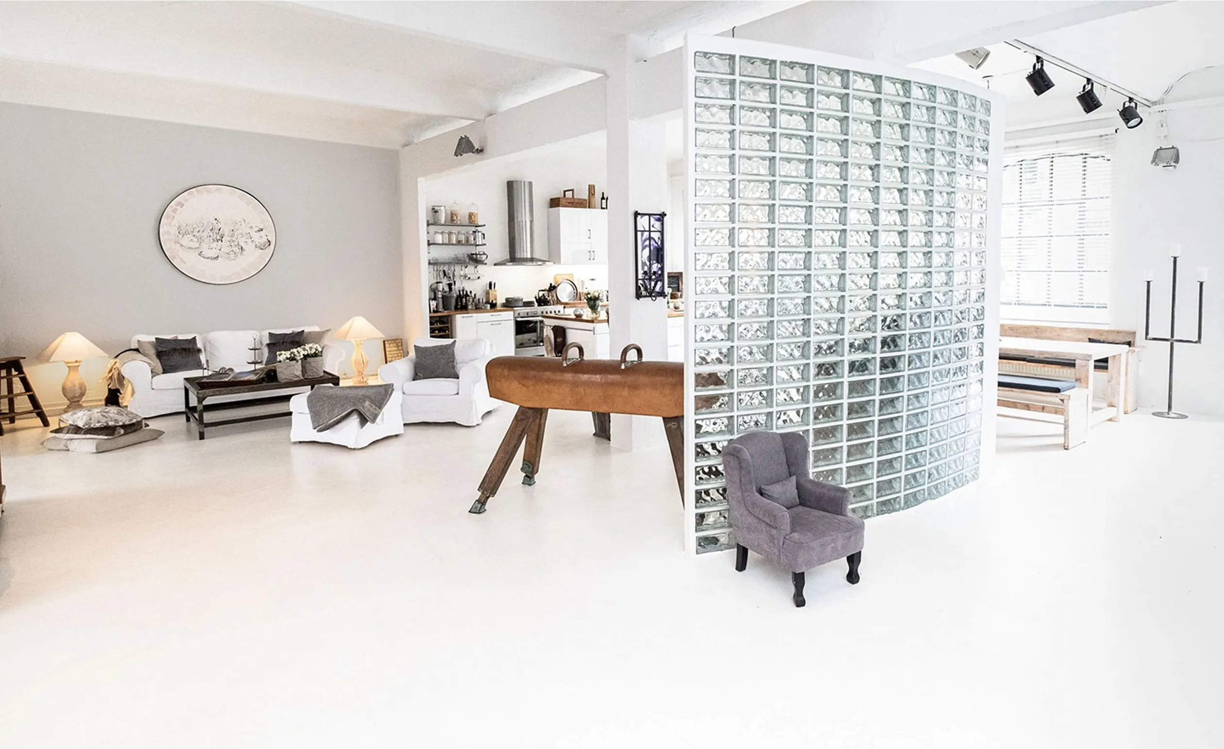 Eventfläche mit Glasbausteinwand – Helles Studio mit Glaswand, Tischkicker und modernen Sitzmöbeln.