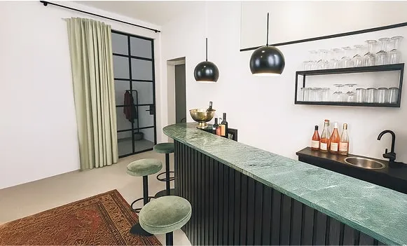 Barbereich mit grüner Theke, schwarzen Hockern und Regal – moderne Mietlocation Hamburg für Events und Shootings.