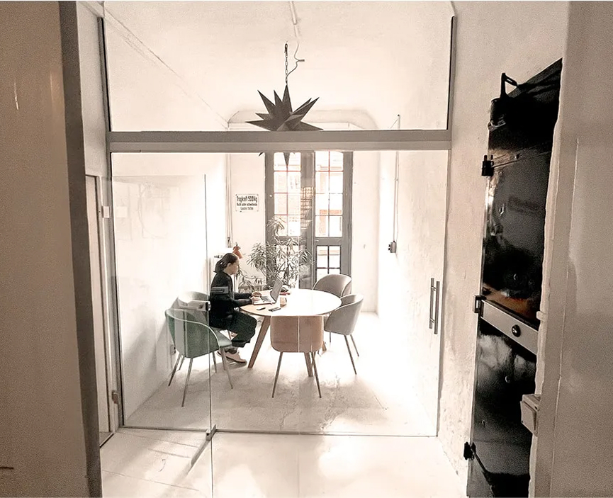 Heller Besprechungsbereich mit rundem Tisch, Designerstühlen, Sternenlampe und französischem Balkon zum Hof.