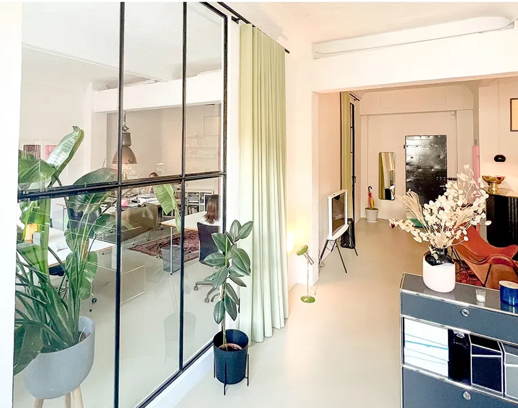 Eingangsbereich mit Pflanzen – Heller Eingang mit Glaswand, grünen Pflanzen und modernen Sitzgelegenheiten.