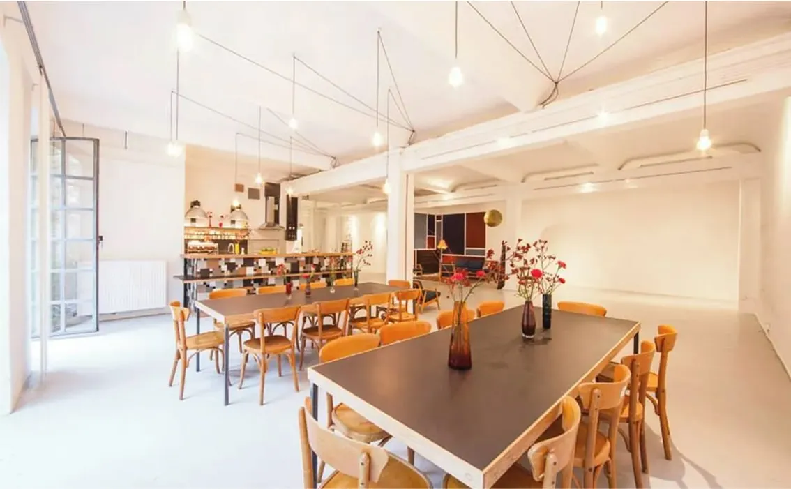 Großer, lichtdurchfluteter Studioraum mit Holztisch und Stühlen – Loft mieten Hamburg für Events und Workshops.